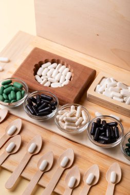 Birçok vitamin, tablet, ahşap kutularda ve cam kaselerde beslenme malzemeleri, vitaminli tahta kaşıklar. İlaçlar, vitaminler, mineraller, diyet takviyeleri. Sağlıklı bir yaşam tarzı. Rustik üst görünüm.