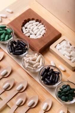 Birçok vitamin, tablet, ahşap kutularda ve cam kaselerde beslenme malzemeleri, vitaminli tahta kaşıklar. İlaçlar, vitaminler, mineraller, diyet takviyeleri. Sağlıklı bir yaşam tarzı. Rustik üst görünüm.