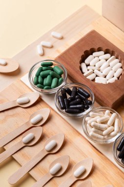 Birçok vitamin, tablet, ahşap kutularda ve cam kaselerde beslenme malzemeleri, vitaminli tahta kaşıklar. İlaçlar, vitaminler, mineraller, diyet takviyeleri. Sağlıklı bir yaşam tarzı. Rustik üst görünüm.
