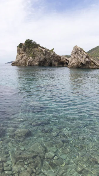 美しい三角形岩と透明な青緑色の海や下部の石 — ストック写真