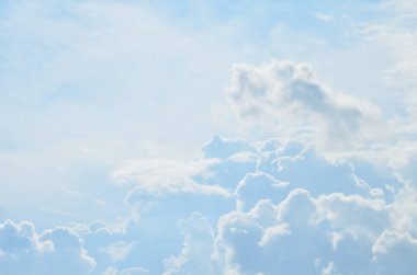 Mavi gökyüzünde yükselen kümülüs bulutları yaz güneşiyle aydınlanır.