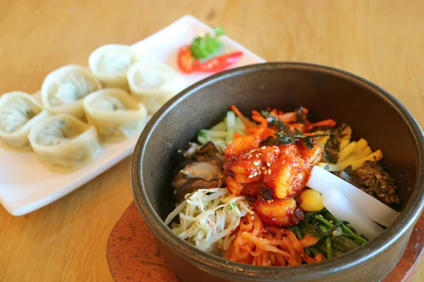 Ağız sulandırıcı Bibimbap ya da Kore Karışık Pirinç Kasesi ve Arka planda Mandu Mandu Mantı