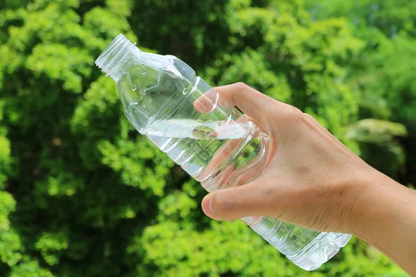 Hand Holding Plastic Bottle Drinking Water Green Foliage — Stock Photo, Image