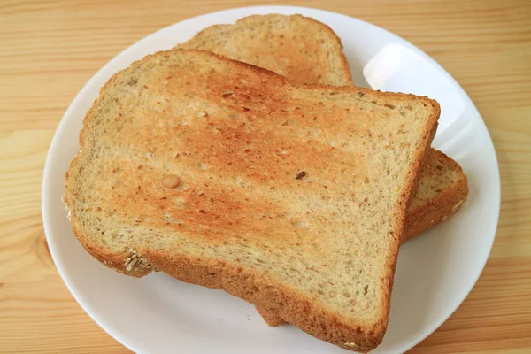 Twee Stukken Volkoren Toast Geserveerd Keramisch Wit Bord Houten Tafel — Stockfoto