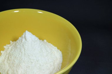 Saf beyaz un sarı seramik kasede, siyah zemin üzerinde izole edilmiş metin ve tasarım için boş alan var.