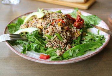 Arugula ve Avokado 'lu Quinoa Salatası Ahşap Masa' da servis edilir.