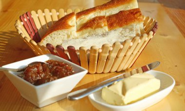 Önplanda ev yapımı incir reçeli ve tereyağlı bir sepet Ermeni ekmeği.