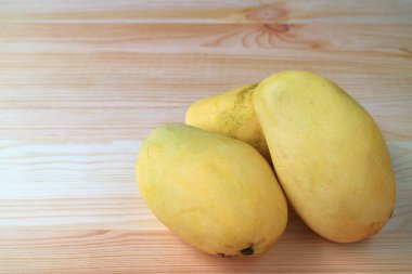 Kapanmış Üç Olgun Ok-Rong Mangosu Tahta Masa üzerinde, Yazı ve Tasarım İçin Boş Alan