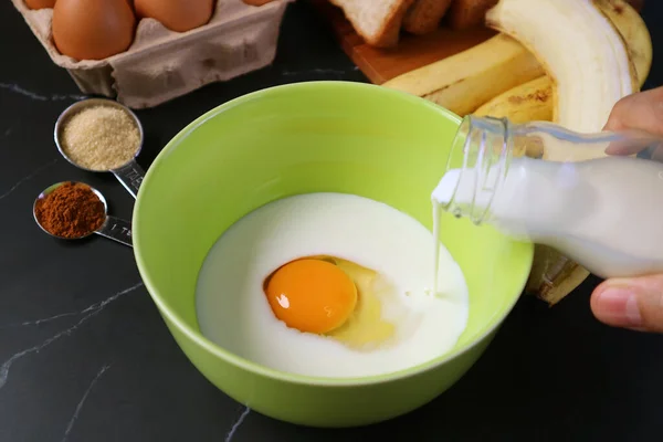 烤香蕉面包布丁用鲜牛奶搅拌碗中的生鸡蛋 — 图库照片