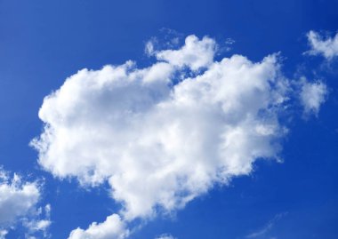 Pofuduk kümülüs bulutları güneşli mavi gökyüzünde süzülüyor