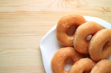 Tahta masadaki beyaz tabakta servis edilen şekerli donutların üst görünümü, metin ve tasarım için boş alan ile