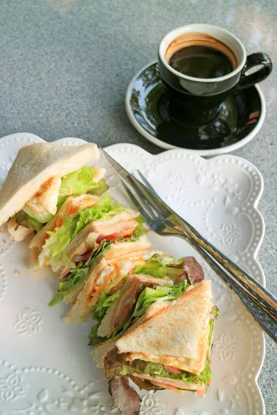 大理石のテーブルの上にホットコーヒーを提供するおいしいサンドイッチのプレート — ストック写真
