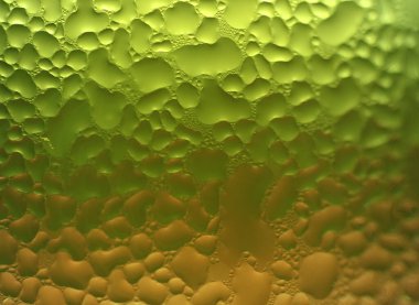 Yeşil ve turuncu renkli camların üzerine seçici bir odak noktasıyla soyut arka plan için makro su damlası dokusu.