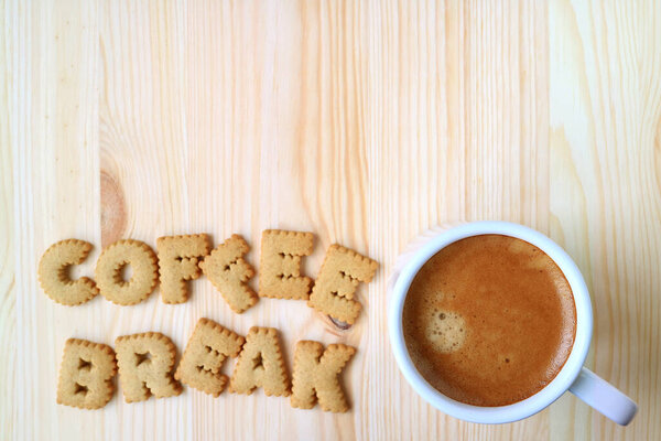 Вид сверху на печенье в форме хабета, написанное словом COFFEE BREE, и чашка кофе на деревянном столе с свободным местом для текста и дизайна