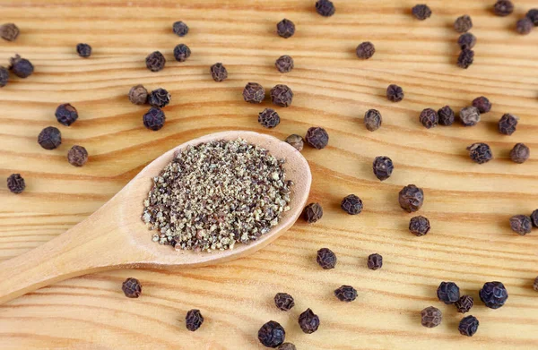 Ground Black Pepper Wooden Spoon Black Peppercorns Scattered Wooden Background — Stock Photo, Image