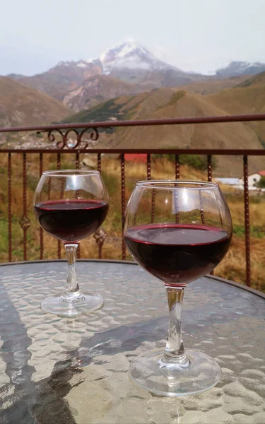 Dois Copos Vinho Tinto Uma Mesa Vidro Com Montanha Coberta — Fotografia de Stock