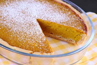 Yakın plan Taze fırınlanmış ve kısmen kesilmiş ev yapımı balkabağı turtası üzerine şeker serpiştirilmiş.