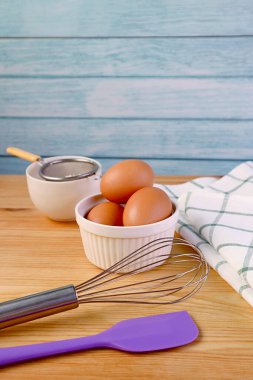 Yumurta, çırpma ve mutfak aletleri ahşap masa üzerinde evde pişirme konsepti için
