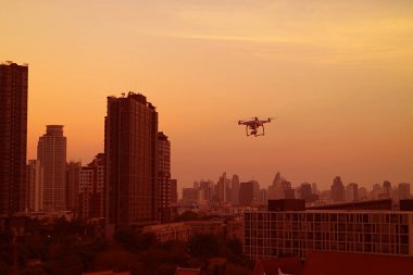 Şehir gün batımında altın turuncu gökyüzünde kızaran bir dronla