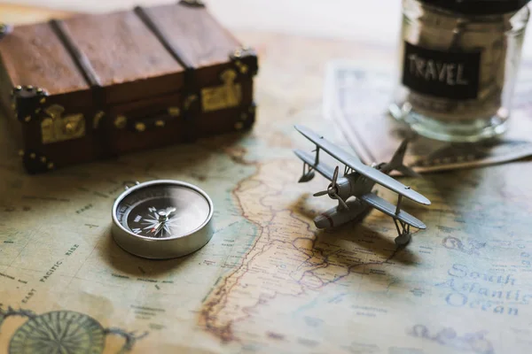 Vacation money saving in a glass with toy airplane and compass on map, Travel concept