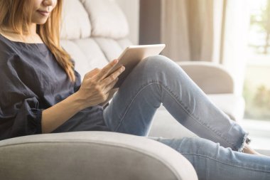 Genç kadın evde kanepede tablet kullanma