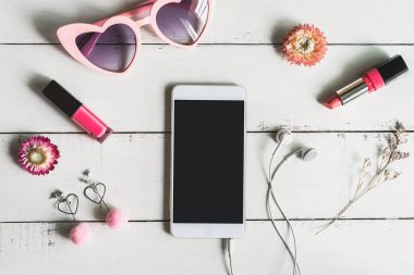 Kozmetik kadın ve moda öğeler üzerinde beyaz tahta arka plan ile akıllı telefon ve kopya alanı, üstten görünüm