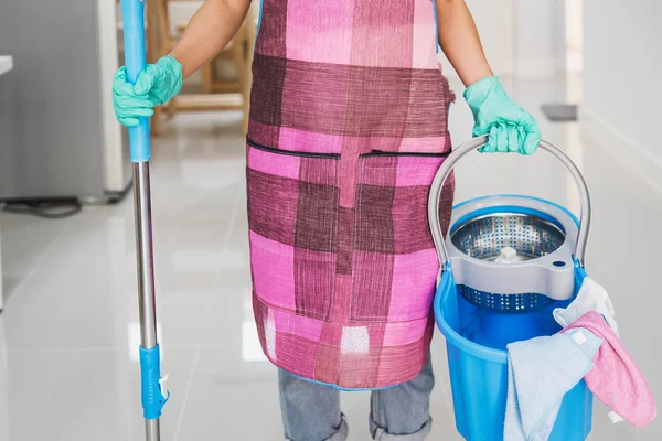 Young woman cleaning floor in living room with mop and bucket, Housework concept