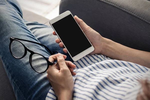 Akıllı telefon olan kadın onun gözlük ve Divan siiting çıkar ve kişinin gözleri evde dinlenmek