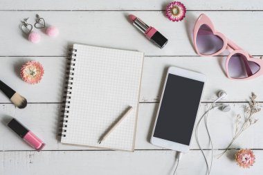 Kozmetik kadın ve moda öğeler üzerinde beyaz tahta arka plan ile akıllı telefon ve kopya alanı, üstten görünüm