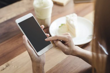 Akıllı telefon kullanarak ve cafede pasta yemeye genç kadın