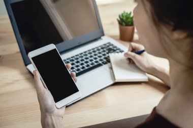 Akıllı telefon ve dizüstü bilgisayar kullanan genç kadın 