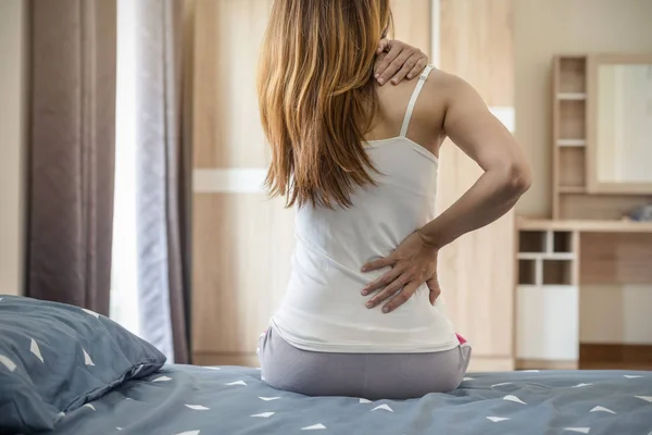 Donna che soffre di mal di schiena sul letto — Foto Stock