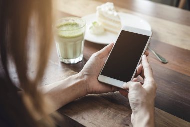 Akıllı telefon kullanarak ve cafede pasta yemeye genç kadın