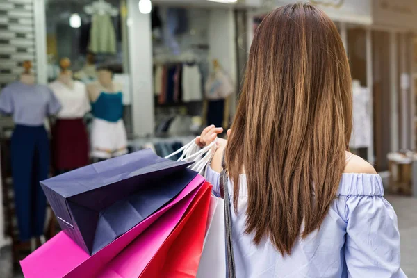 Jonge vrouw met boodschappentassen in de winkel — Stockfoto