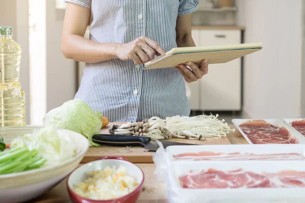 Ung kvinna som använder sin pekplatta i köket — Stockfoto