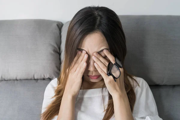 年轻女子摘下眼镜, 坐在沙发上 — 图库照片