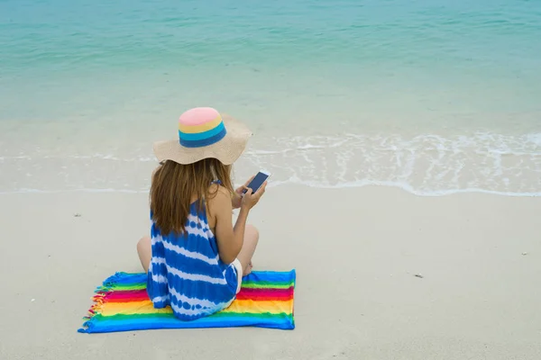 Junge Frau entspannt sich und benutzt Handy am tropischen Strand — Stockfoto