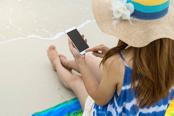 Молода жінка розслабляється і використовує мобільний телефон на тропічному маяку — стокове фото
