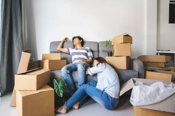 Young tried couple moving in new home, sitting and relaxing on s