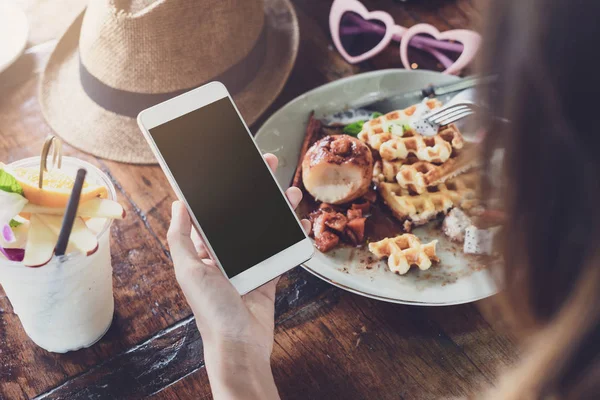 Young woman using smart phone and enjoy eating dessert in cafe — Stock Photo, Image