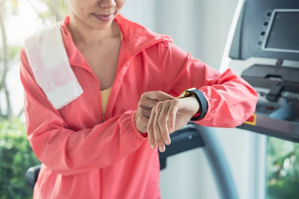 Young sport woman using smart watch on treadmill in gym