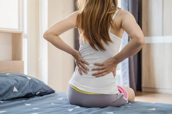 Donna che soffre di mal di schiena sul letto — Foto Stock