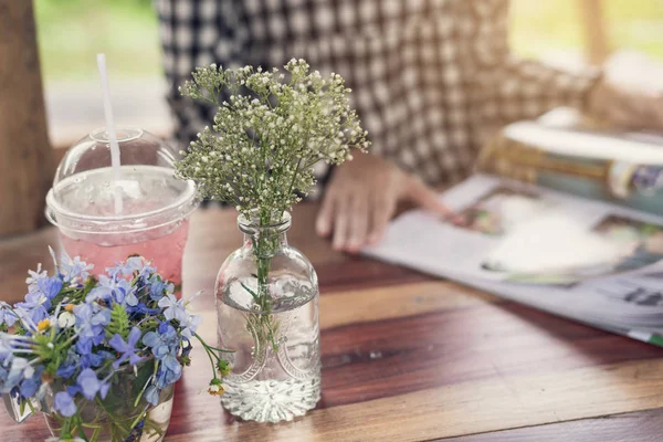 Giovane donna che legge rivista al ristorante con succo e bouque — Foto Stock