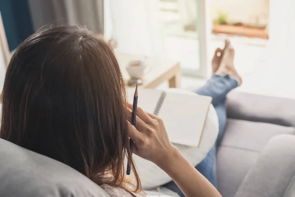 Tânără femeie scriind jurnal la casa confortabilă pe canapea în camera de zi — Fotografie, imagine de stoc