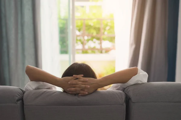 Jonge vrouw ontspannen op de Bank in gezellig huis en op zoek naar buiten in — Stockfoto