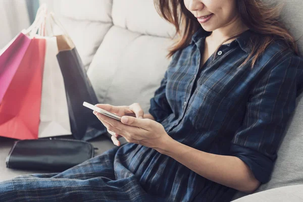 Gelukkige Aziatische vrouw zittend op de Bank en het gebruik van slimme telefoon voor winkel — Stockfoto