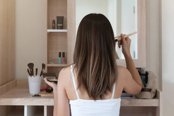 Jeune femme assise et faisant du maquillage devant le miroir en robe — Photo