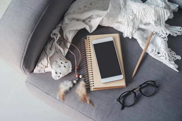 Телефон, блокнот і окуляри на дивані у вітальні вдома — стокове фото