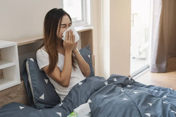 Asian kobieta czuje się dobrze i kichanie na The łóżko — Zdjęcie stockowe