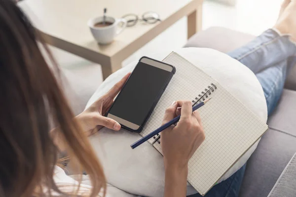 Mujer joven usando teléfono inteligente en casa acogedora en el sofá en la sala de estar — Foto de Stock